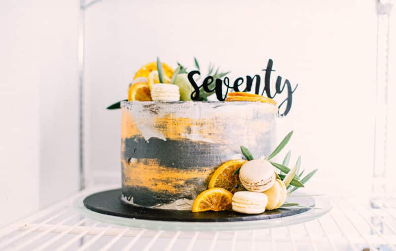 Seventieth birthday milestone cake with citrus, macarons and greenery for outback dining celebration.