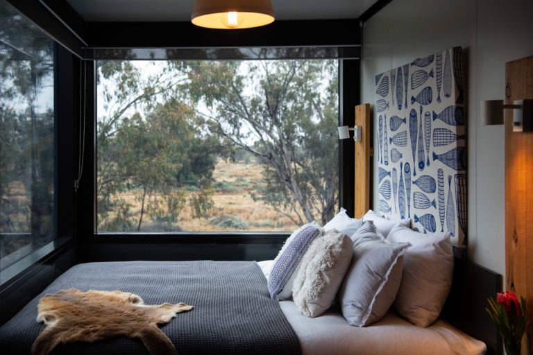 Sky Suite bedroom at Callubri Station overlooks outback NSW bushland through large window.