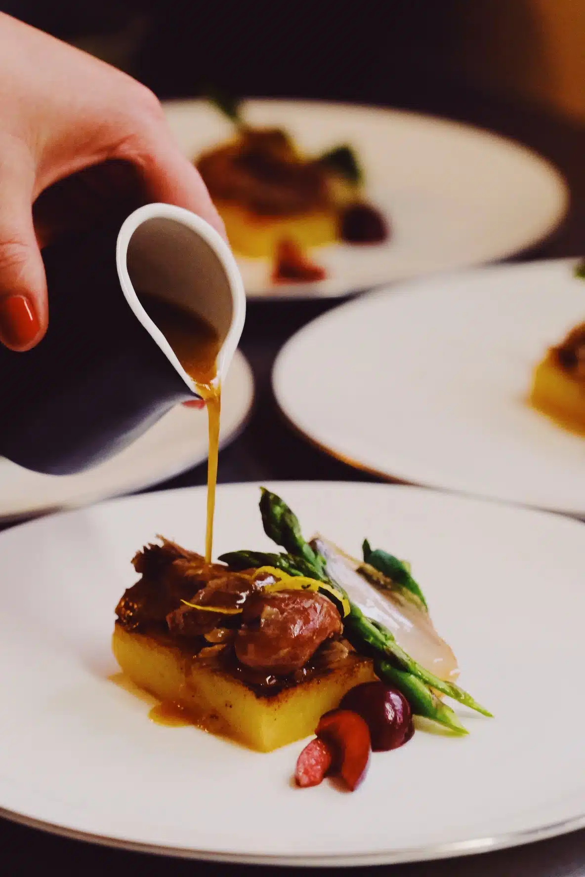 Chef pouring sauce over duck confit at Callubri Station's fine dining outback restaurant.