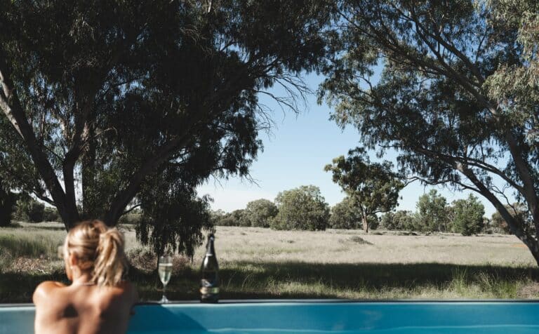 Women enjoying a glass of wine in a mineral shipping container pool in the outback